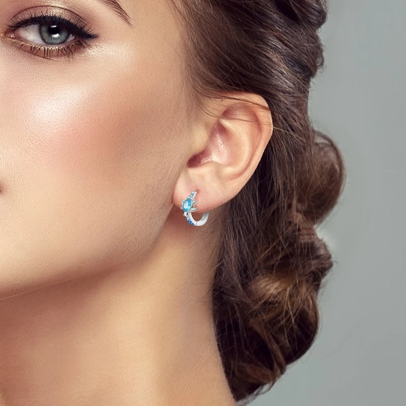 Close-up of a blue turtle hoop earring worn on one ear