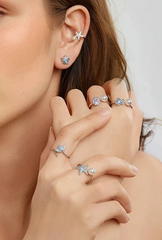 Ocean-inspired rings worn on hand with matching earrings
